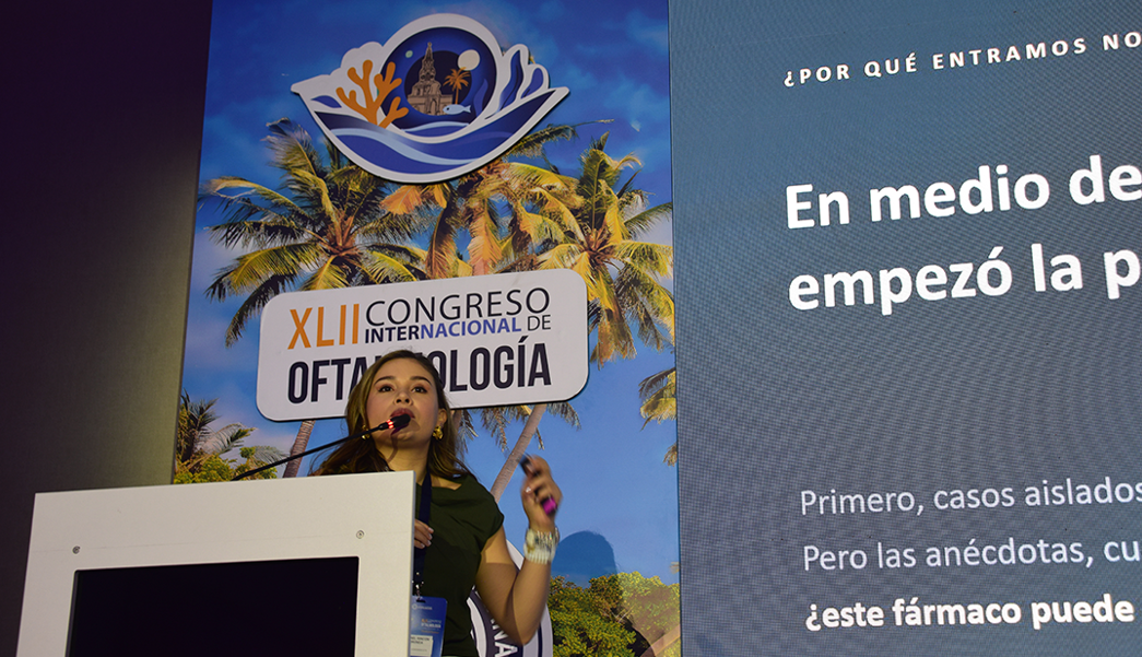 Female presenter speaks at a podium during a medical conference; banner reads XLII Congreso Internacional de Oftalmología with palm trees in the background